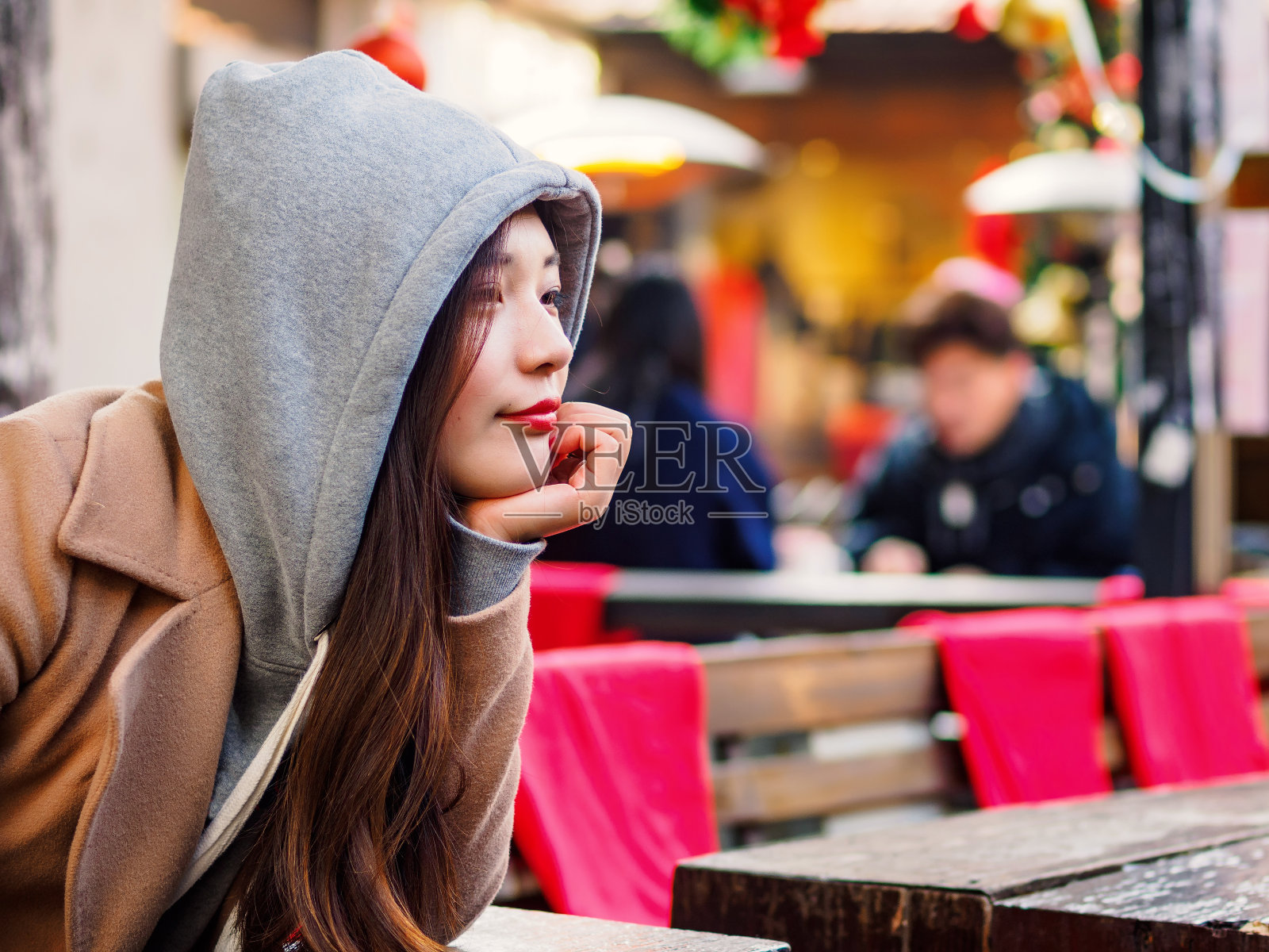 在上海新天地，一个性感的中国年轻女孩双手托着下巴，闭着眼睛坐在咖啡馆里，做着白日梦。照片摄影图片