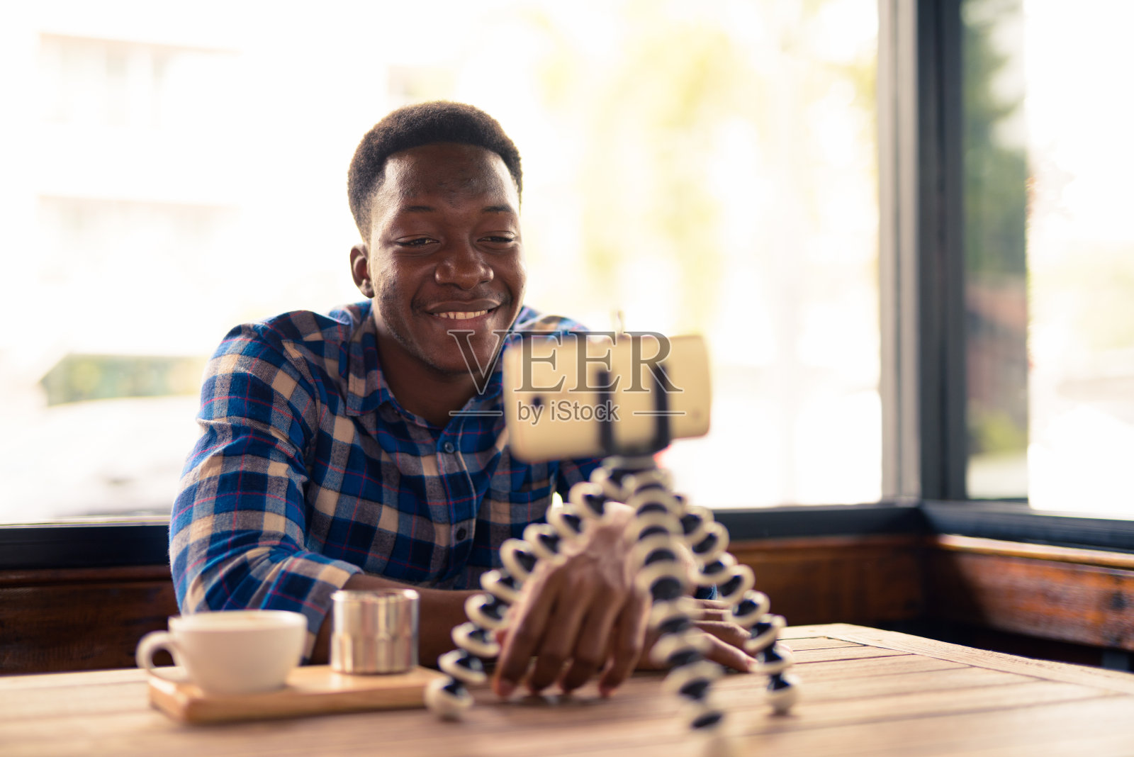 年轻英俊的非洲男子坐在咖啡店里的肖像照片摄影图片
