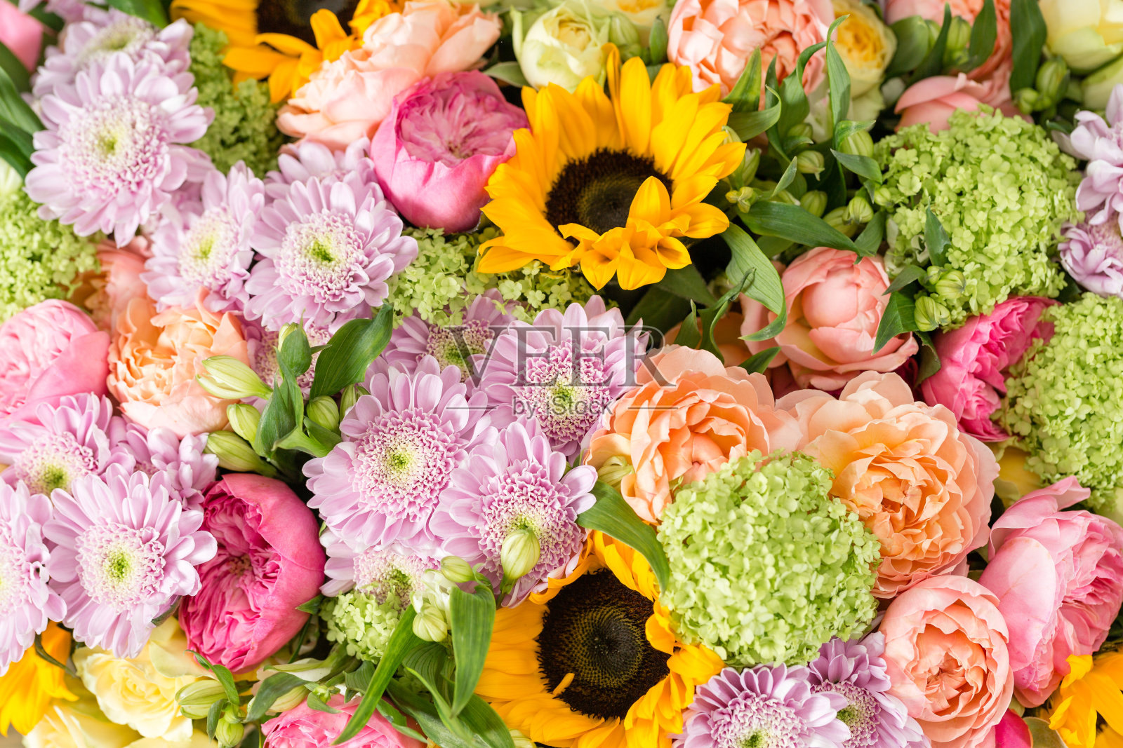 木桌上的花瓶里装着一束美丽的混合鲜花。花店花匠的工作。向日葵、菊花和玫瑰的鲜艳组合。全屏背景照片摄影图片