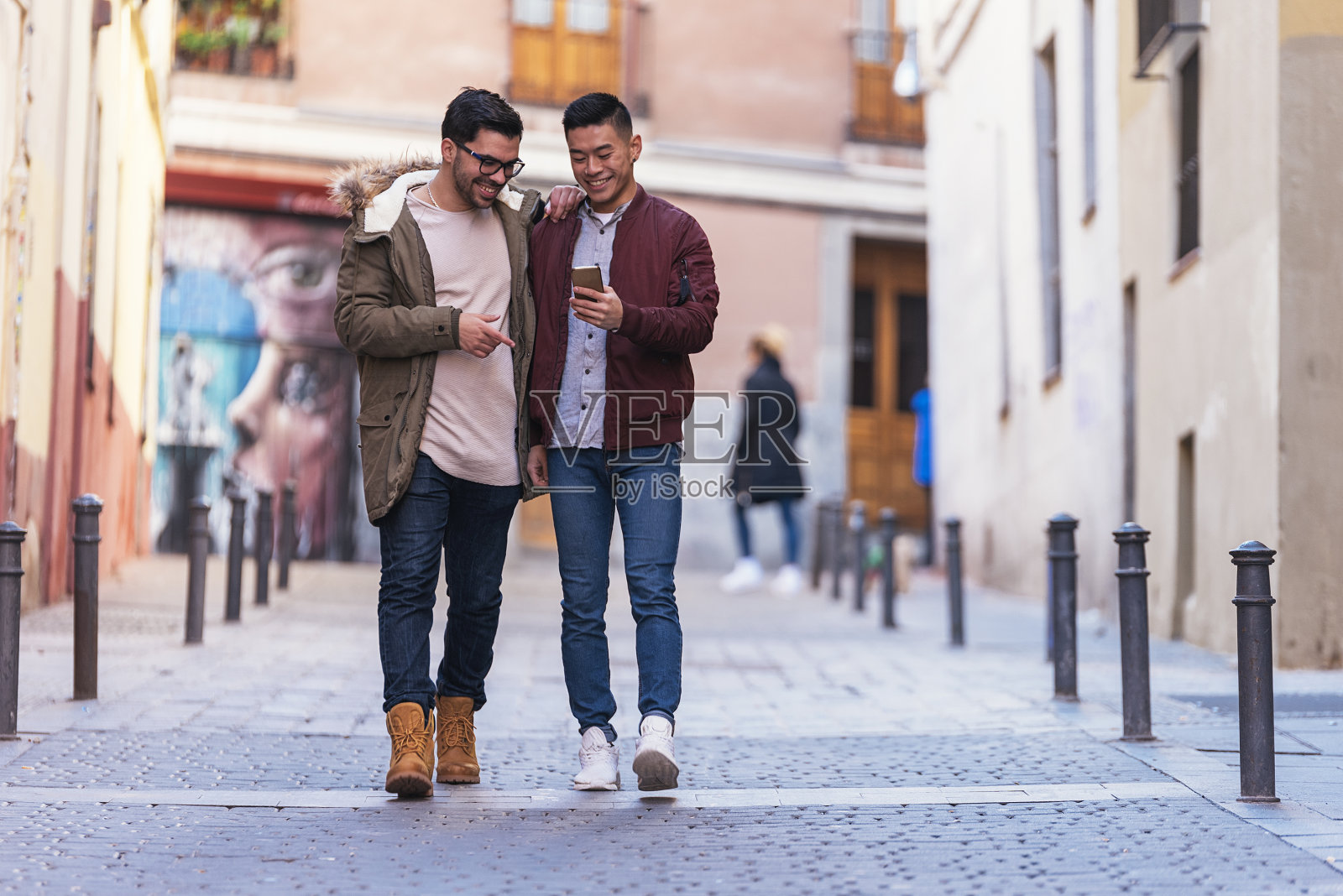 两个开心的朋友在街上玩手机。照片摄影图片