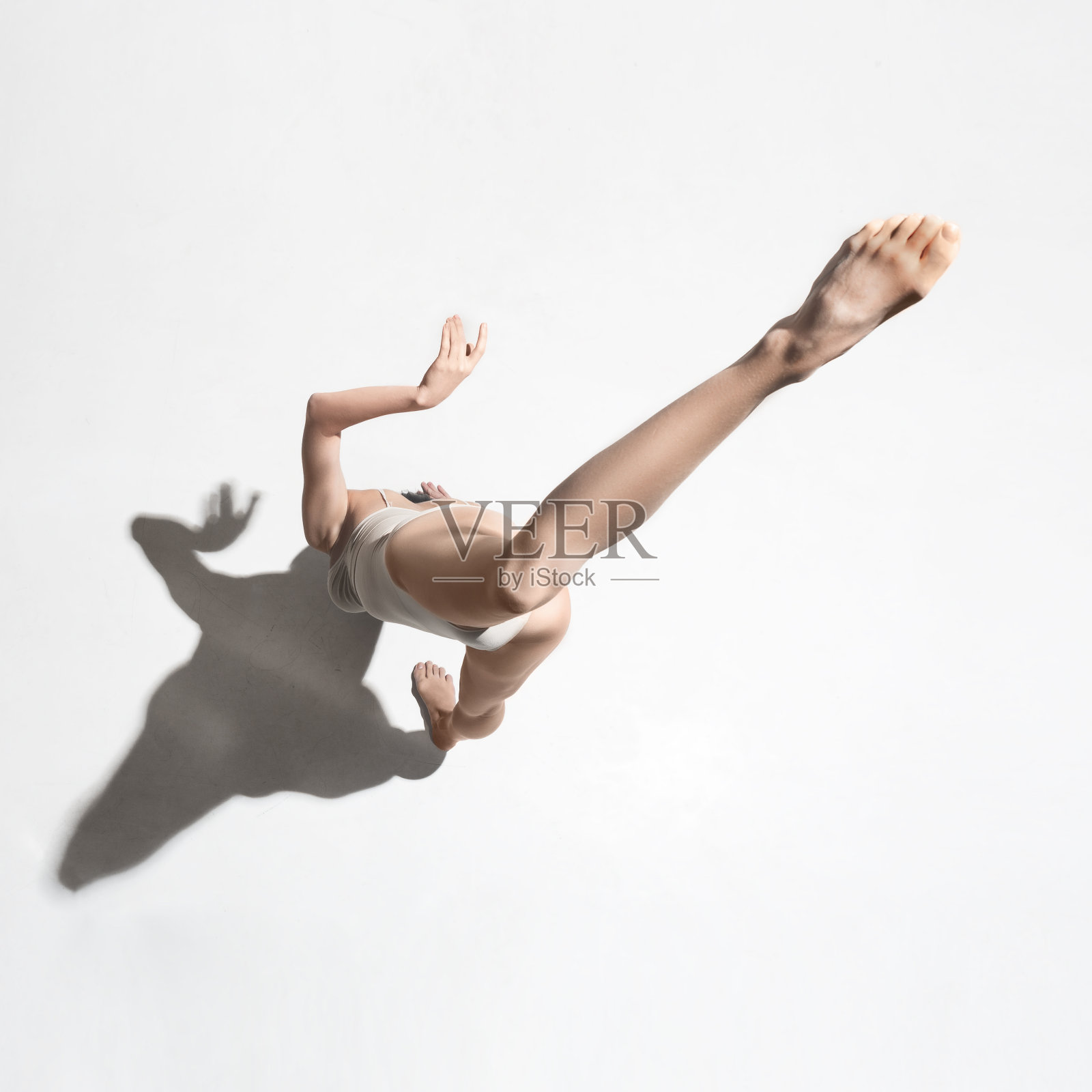 年轻美丽的舞者在米色连衣裙上跳舞在灰色的背景照片摄影图片