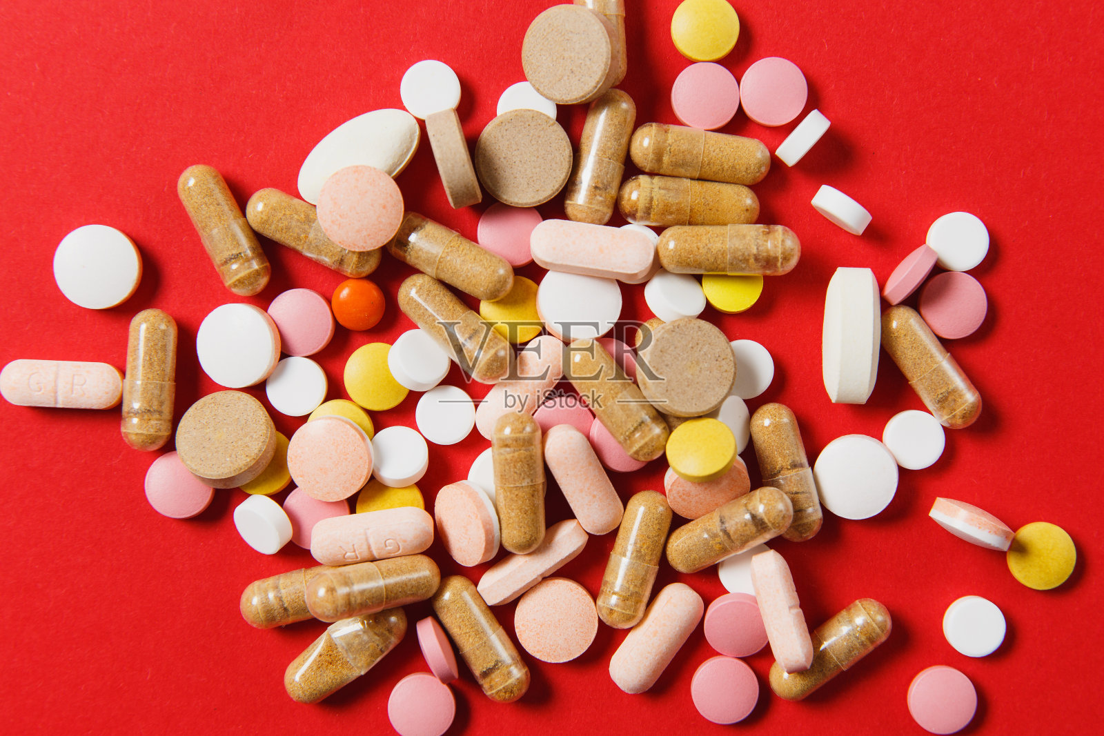 药白色七彩圆片排列在红色背景上。阿司匹林，胶囊设计。健康、治疗、选择健康的生活方式理念。广告版面复制。照片摄影图片