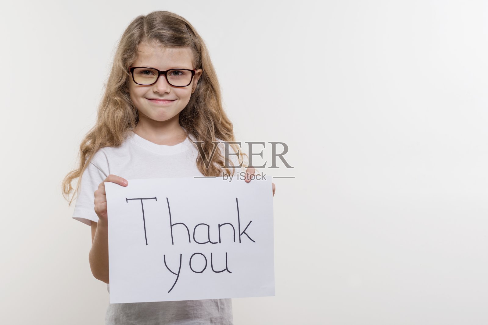 女孩拿着一张纸，上面写着“谢谢你”。白色backgrounde照片摄影图片
