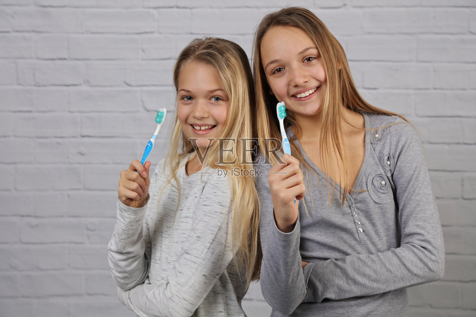 两个漂亮女孩的肖像孩子们完美的微笑着拿着牙刷。儿童牙科保健、口腔卫生的概念照片摄影图片