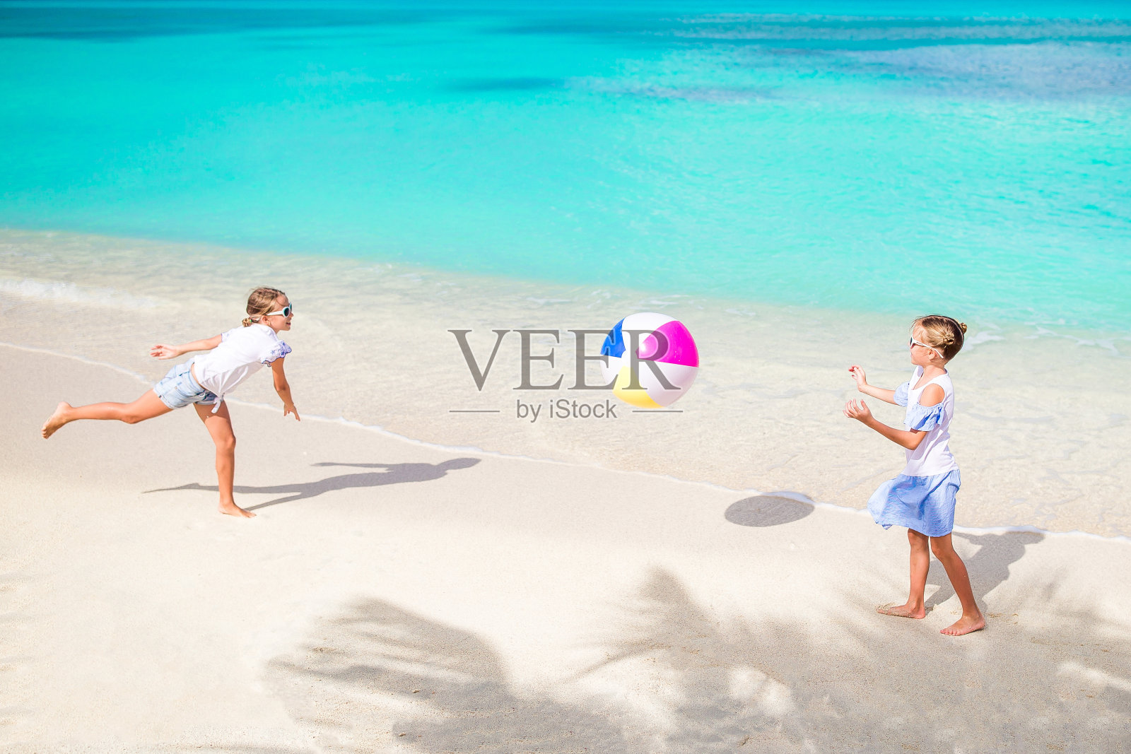 可爱的小女孩在沙滩上玩球照片摄影图片