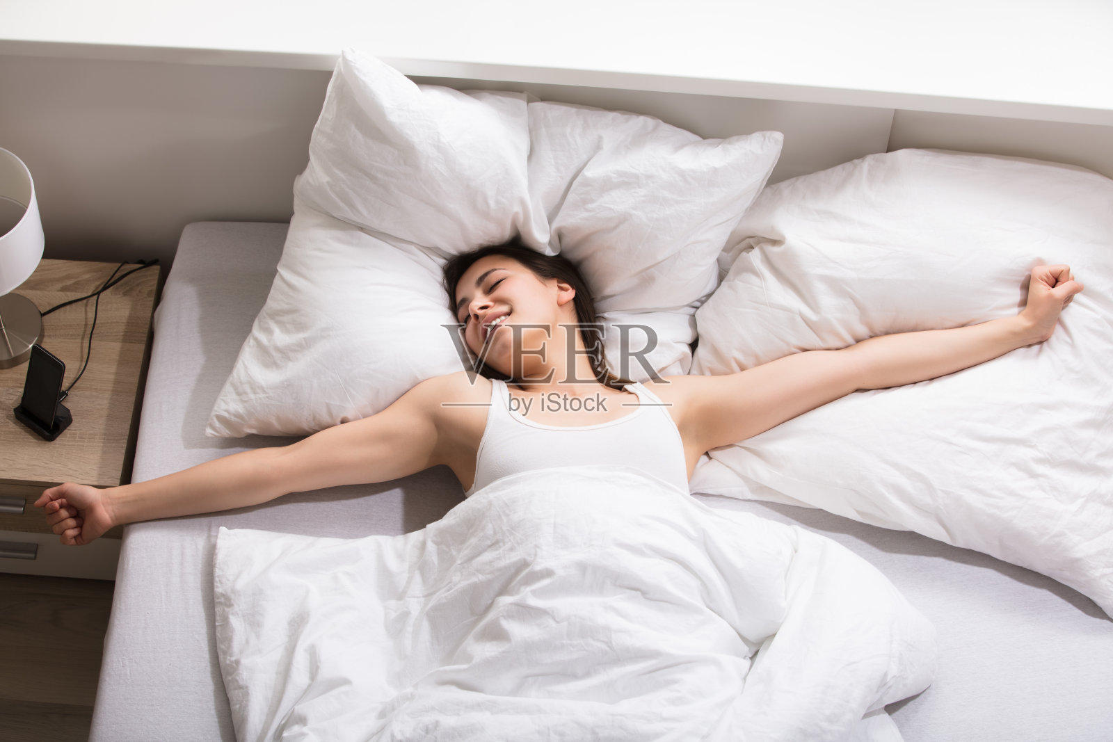 瞌睡女人在床上伸懒腰照片摄影图片