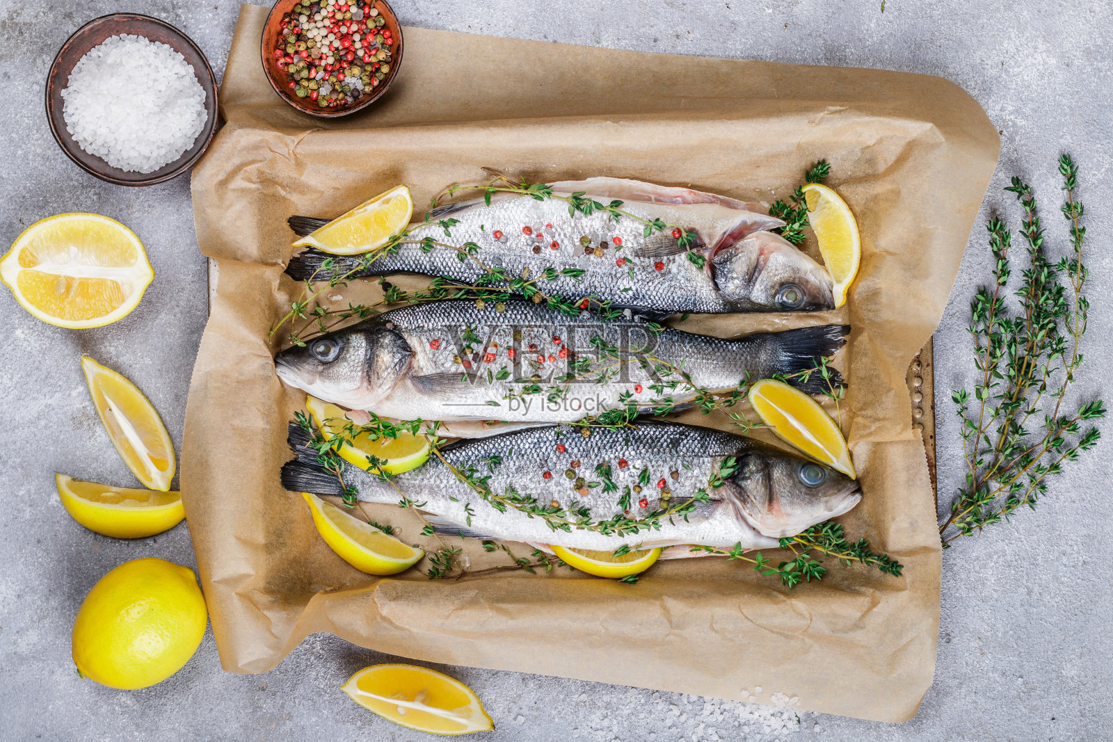 新鲜的生鱼(花鲈)可以与柠檬，百里香，海盐和粉胡椒一起烘烤。准备一顿丰盛的晚餐。有选择性的重点照片摄影图片