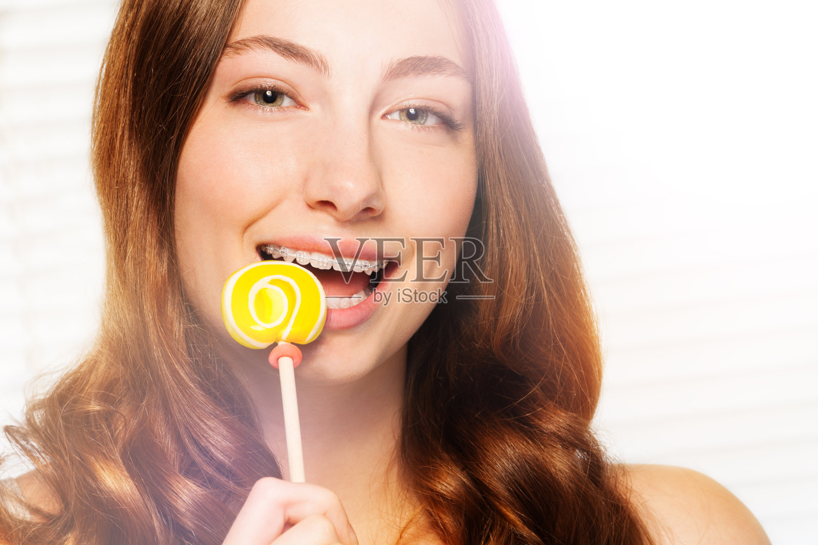 戴着牙套的女人咬掉了漩涡棒棒糖照片摄影图片