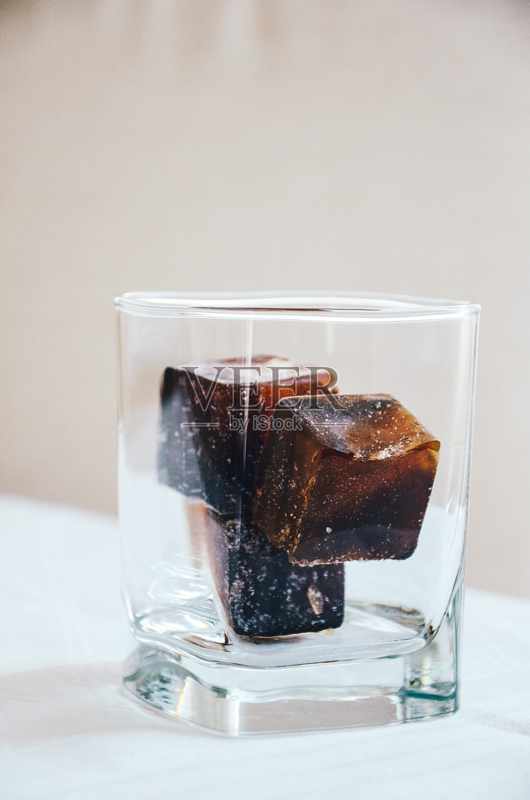 3块用咖啡制成的冰块放在玻璃杯中，以备爽口的咖啡饮料，白色背景照片摄影图片