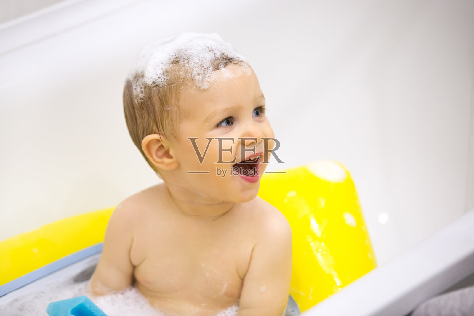 兴奋的孩子用玩具和泡沫在头上洗澡照片摄影图片
