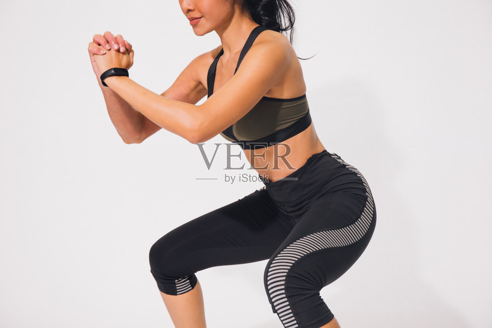 年轻的运动肌肉女性做下蹲隔离在白色的背景。穿着运动服进行锻炼的妇女照片摄影图片