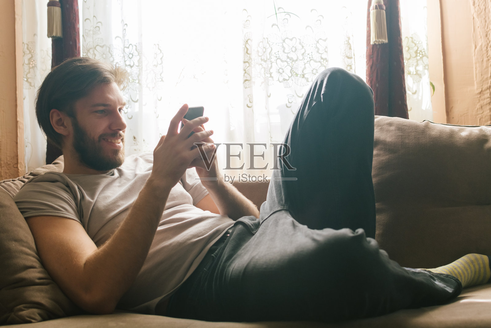年轻人坐在客厅的沙发上打电话照片摄影图片