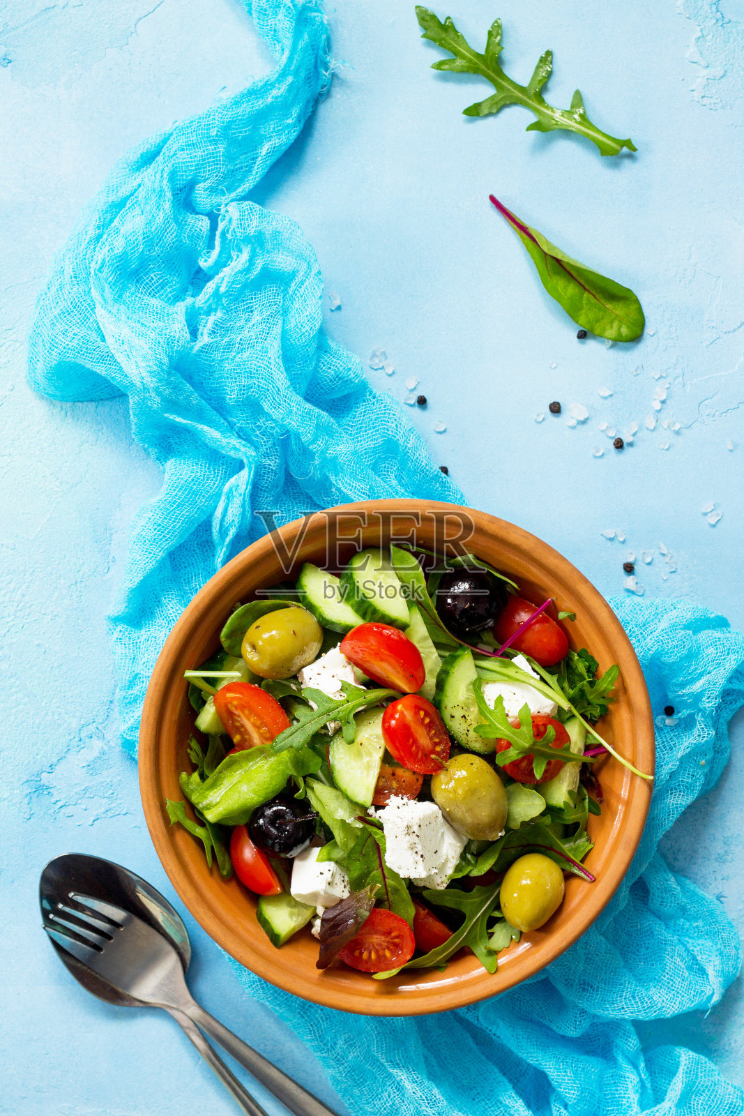 希腊沙拉配新鲜蔬菜，羊乳酪和黑橄榄，放在蓝色的石头或混凝土桌上。复制空间，俯视图平铺背景。照片摄影图片
