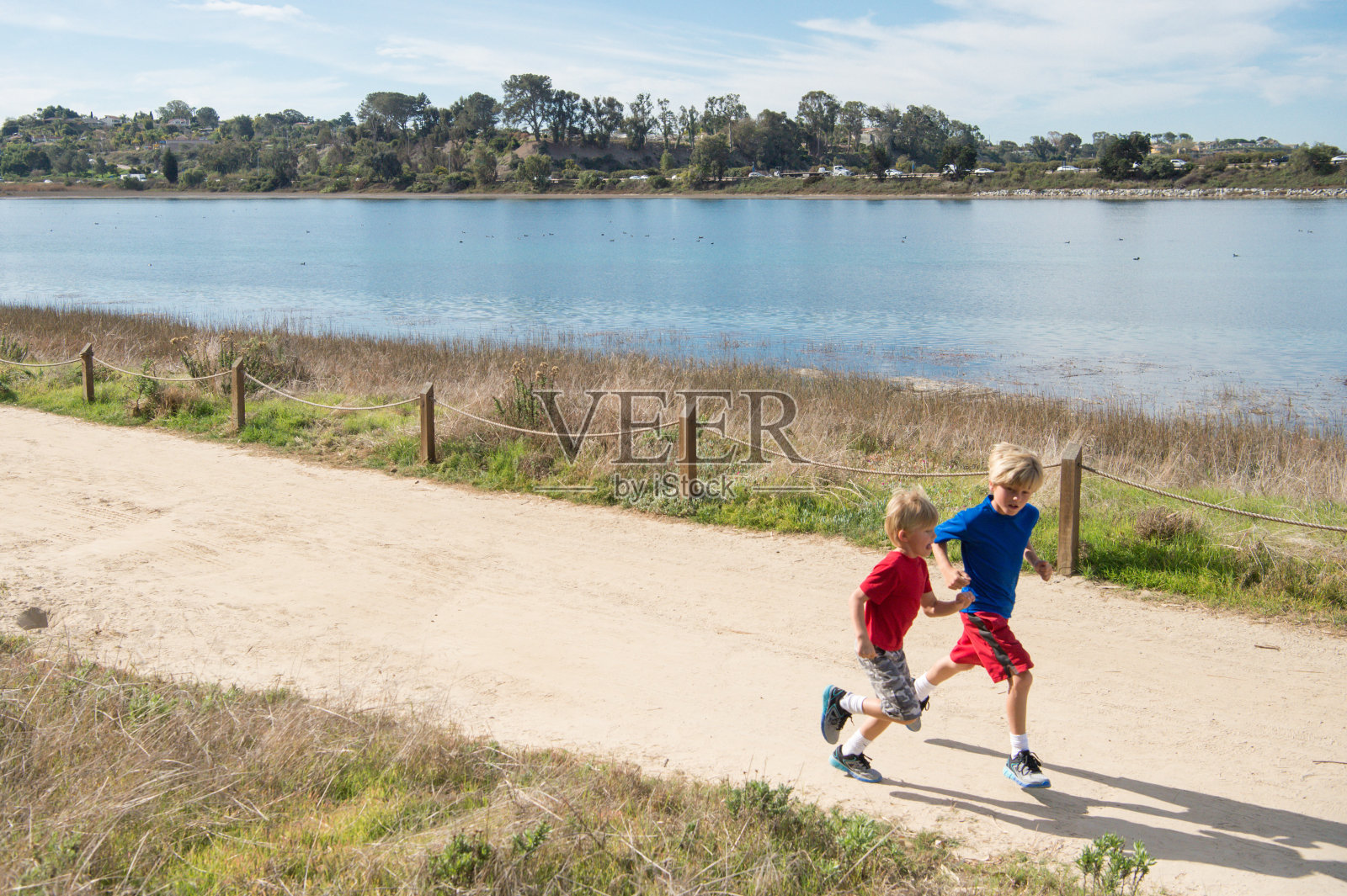 两个孩子在泥土路上沿着泻湖奔跑照片摄影图片