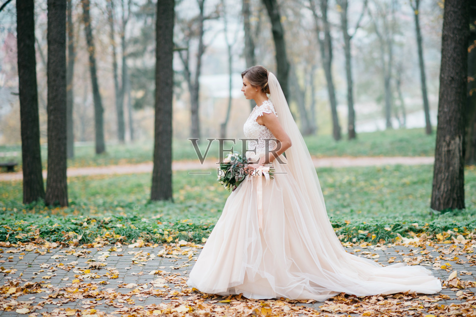 美丽的新娘手捧婚礼花束在公园外照片摄影图片