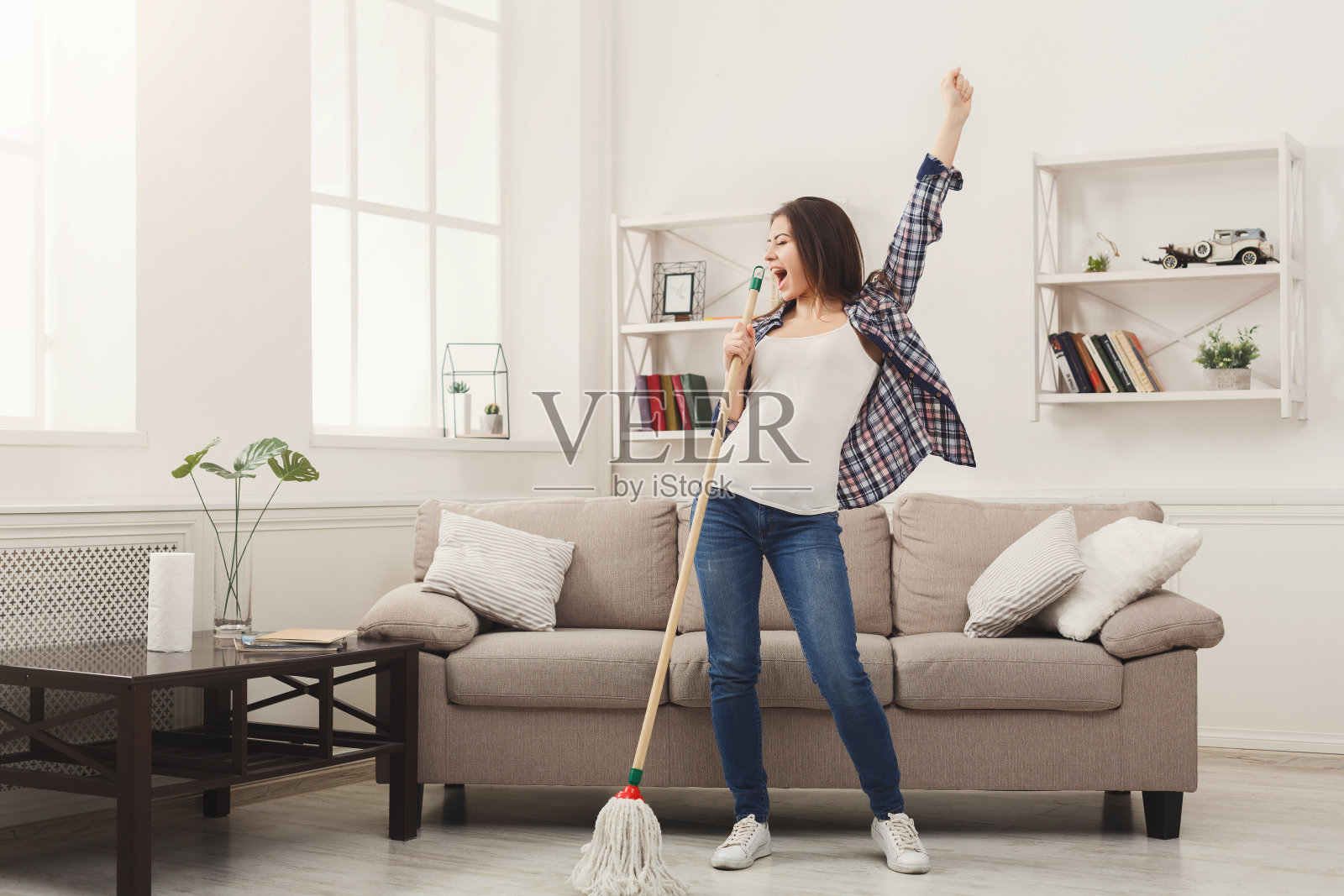 快乐的女人用拖把打扫房间，玩得很开心照片摄影图片