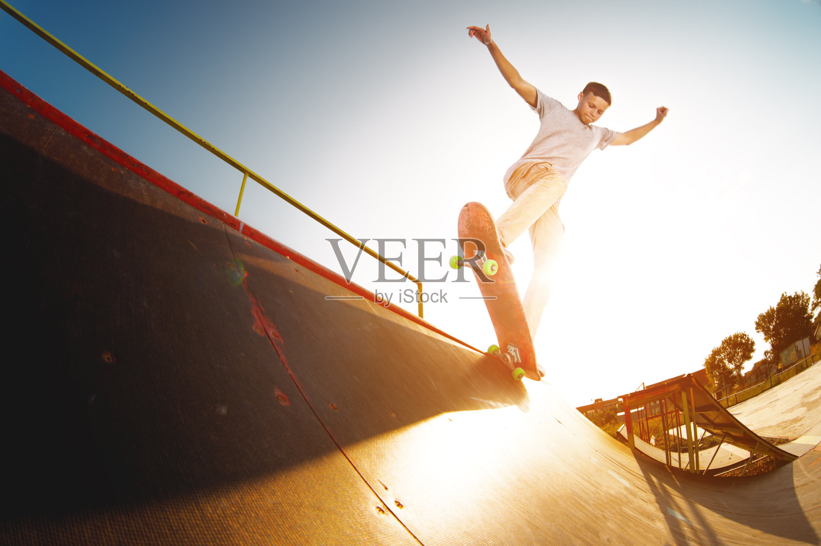 在一个滑板公园里，一个十几岁的滑板手挂在滑板的斜坡上照片摄影图片