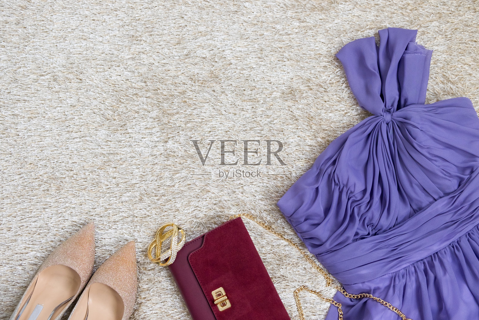 女装的紫色服装，金色高跟鞋女鞋和钱包上的合成奶油皮草纹理与复制空间。平躺照片摄影图片