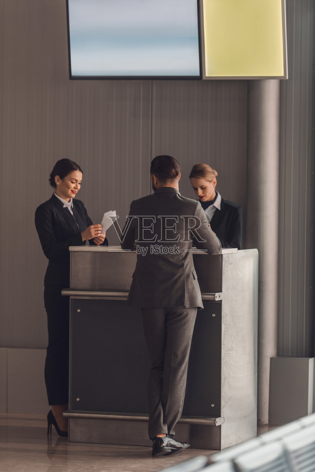 后视图的商人站在机场登记柜台照片摄影图片
