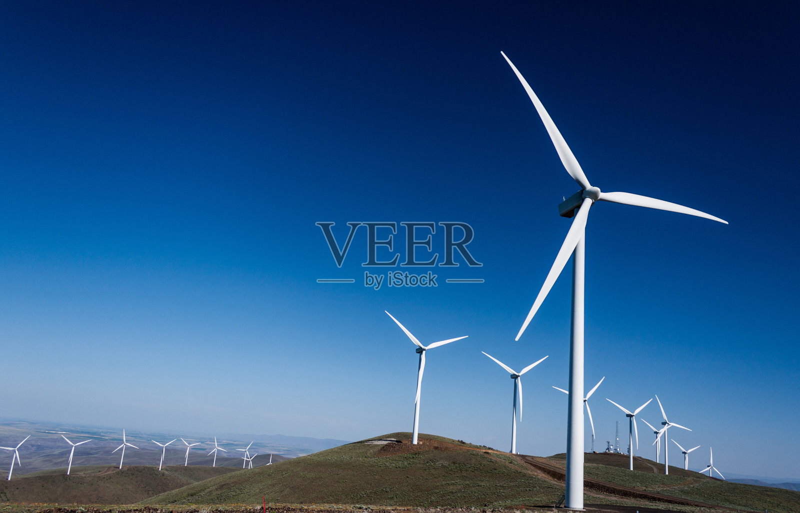 蓝天下连绵起伏的山峦上的风力发电机照片摄影图片