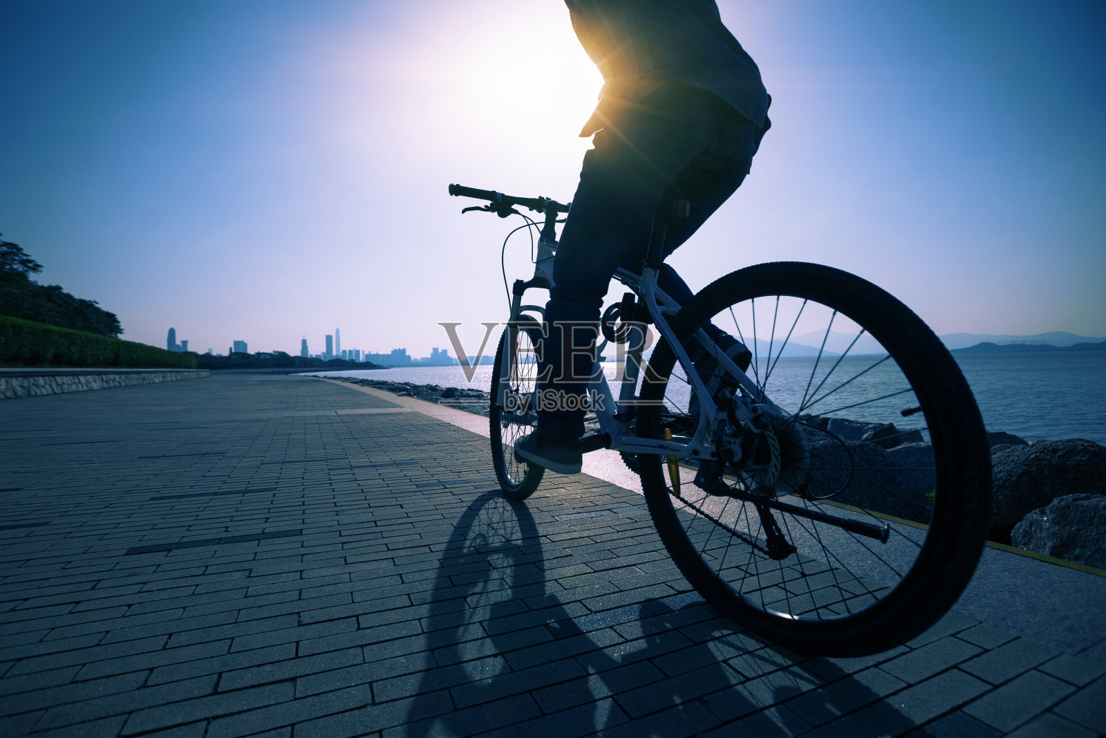 剪影骑自行车的人在日出的海岸公路上骑自行车照片摄影图片
