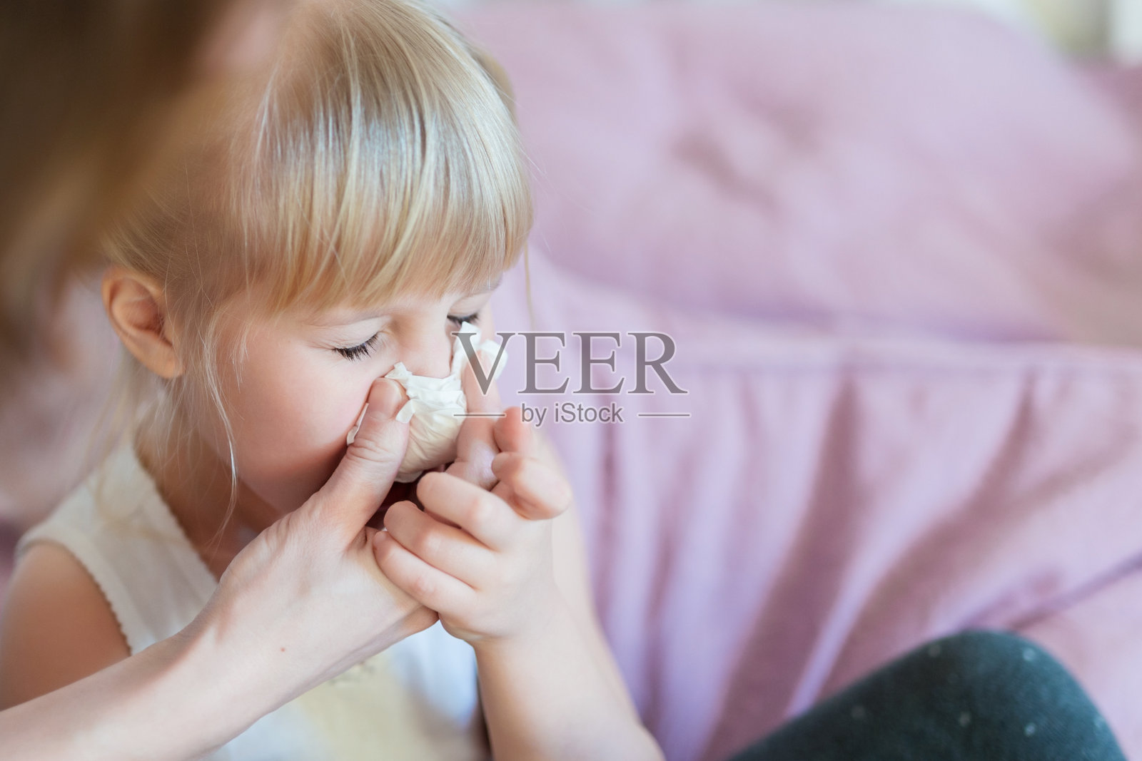 流鼻涕的孩子。妈妈帮孩子用纸巾擤鼻涕。季节性疾病照片摄影图片