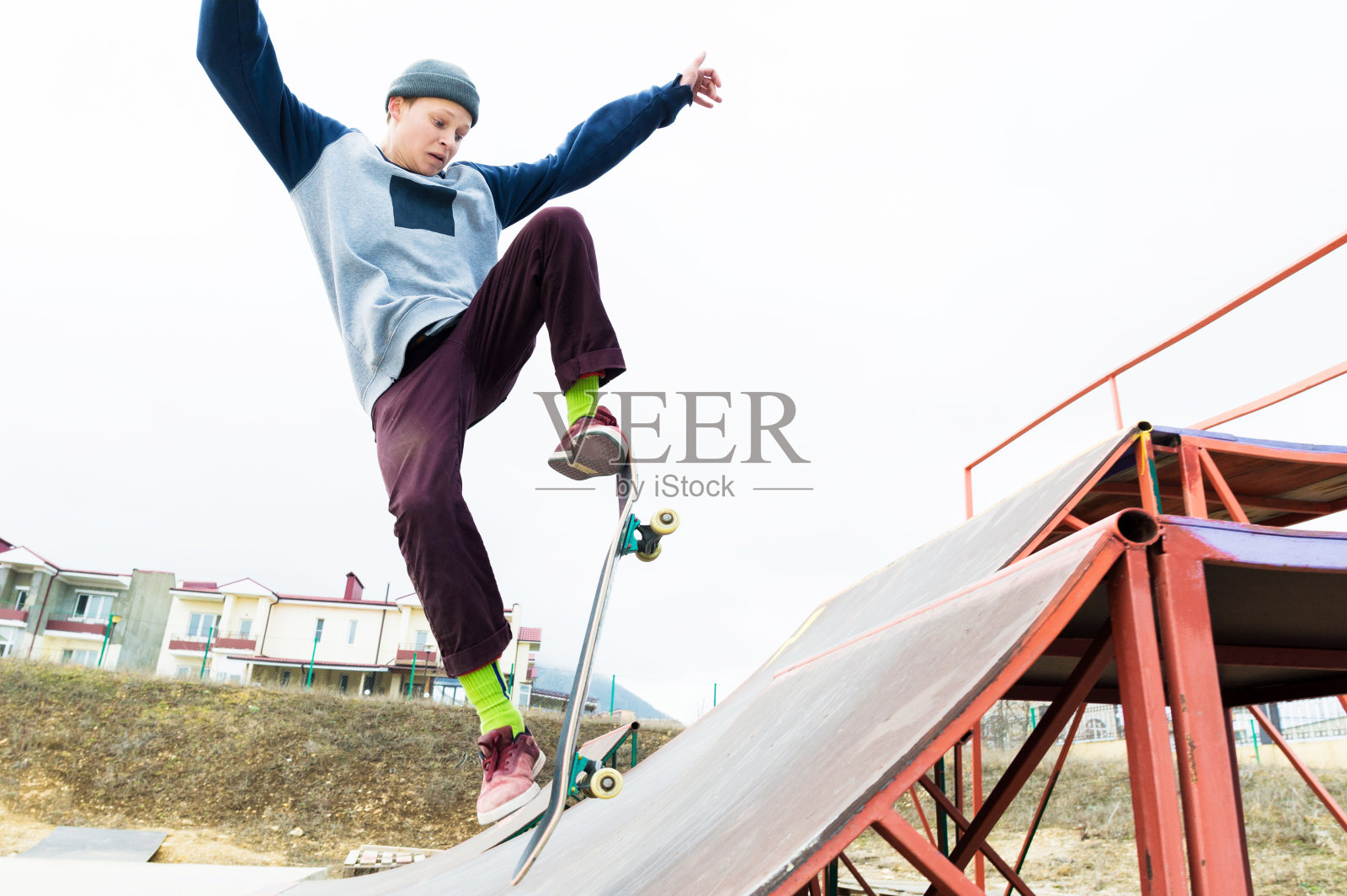 一个戴着帽子玩滑板的少年在坡道上跳来跳去，耍了个小把戏。一个滑板运动员在空中飞照片摄影图片