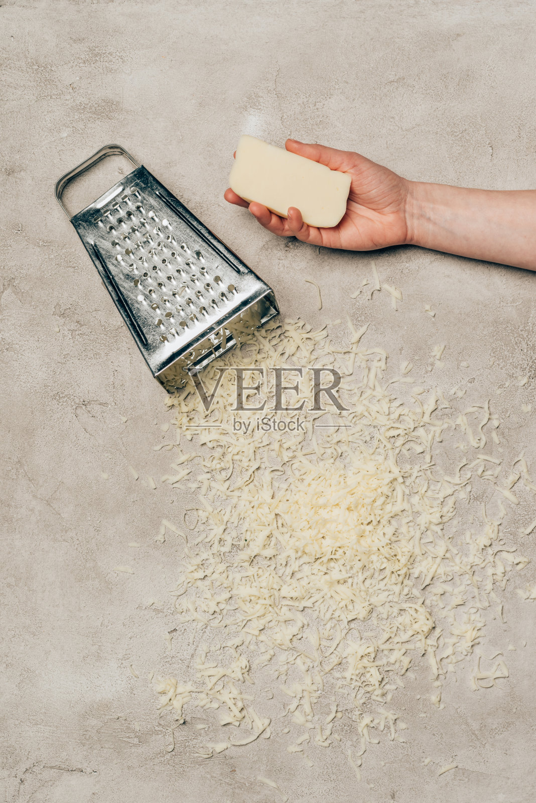 手握奶酪由磨碎器在光背景上的特写视图照片摄影图片