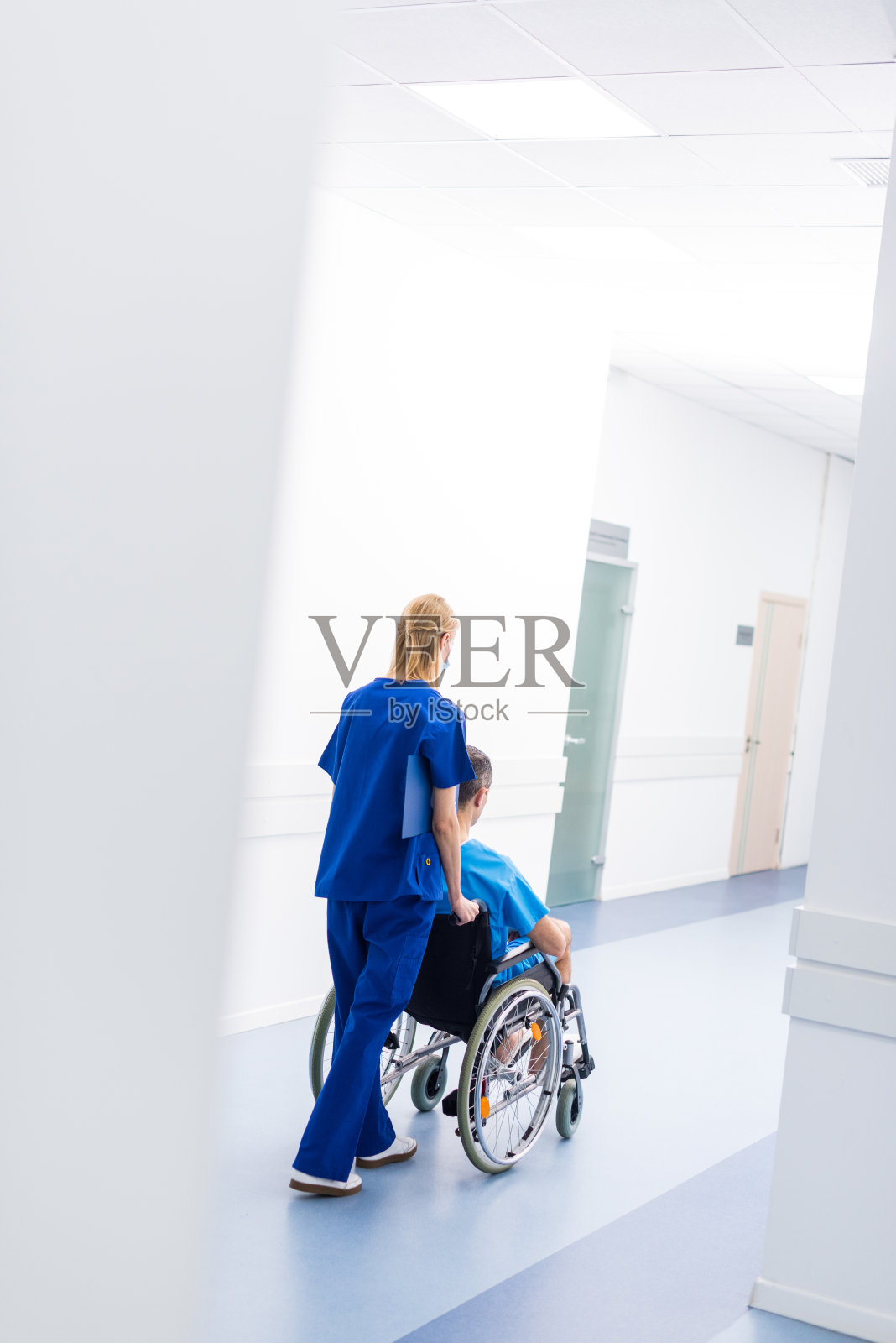 在医院走廊里坐轮椅的外科医生和不安的病人的后视图照片摄影图片