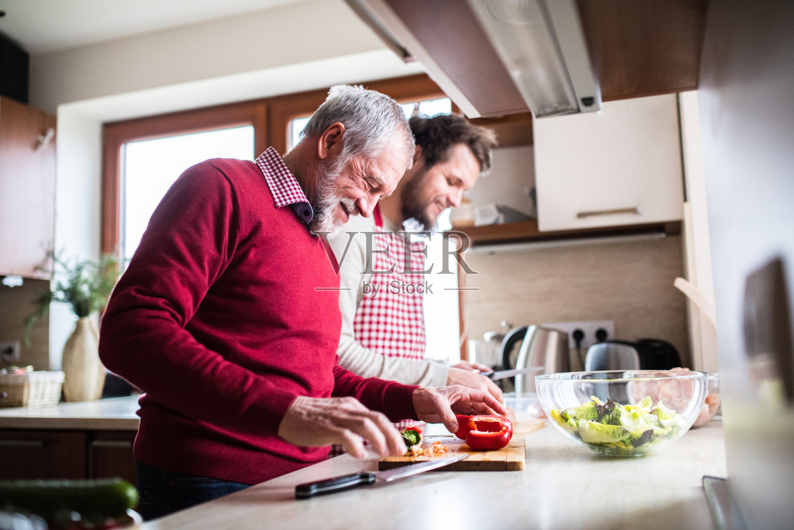 时髦的儿子和他的老父亲在厨房做饭。照片摄影图片
