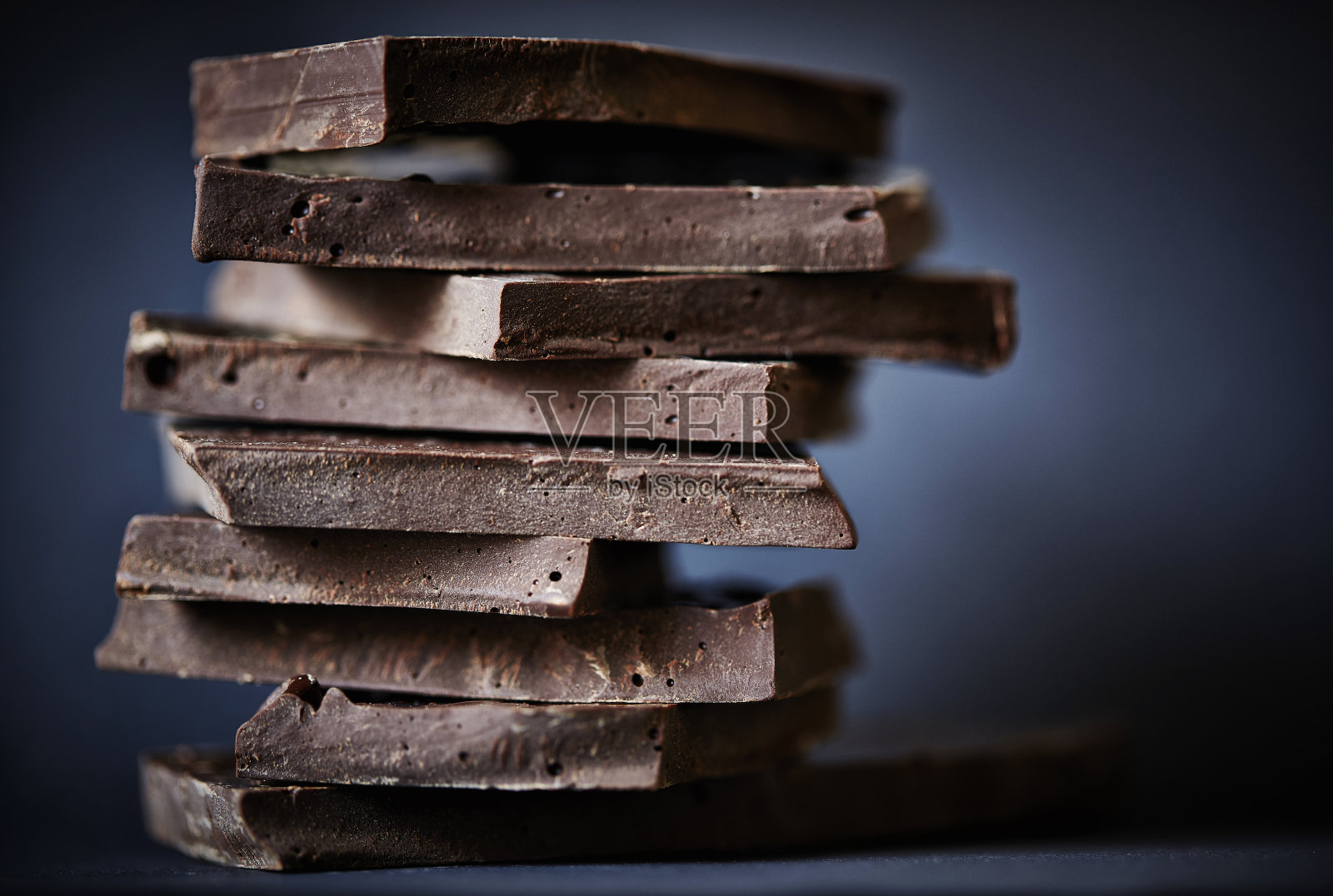 巧克力碎块堆在深色的背景上。照片摄影图片