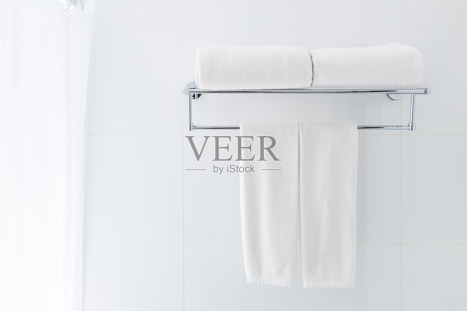 白色浴巾挂在浴室附近的白色浴巾架上，有利于清洁和新鲜的主题或刷新概念照片摄影图片