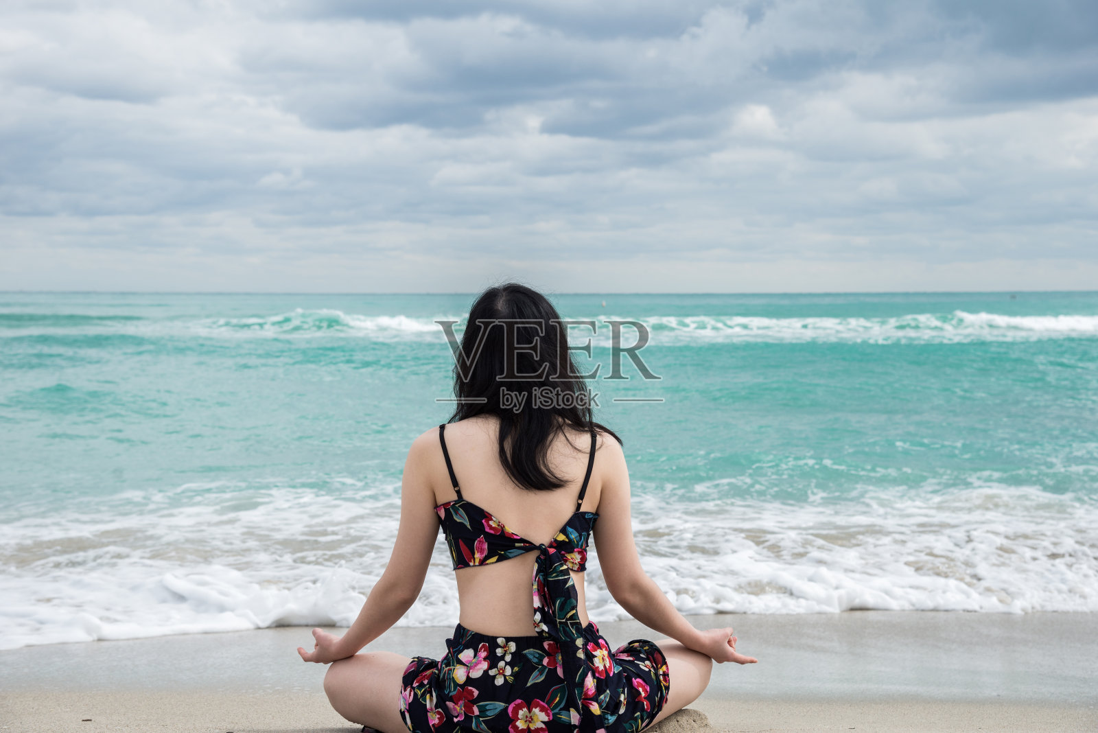 后视图的女人坐在莲花位置上的海滩照片摄影图片