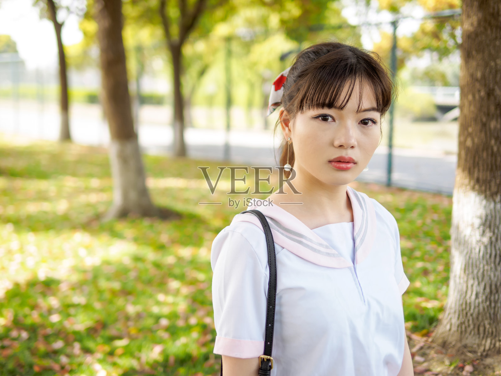 这是一幅美丽的亚洲女学生的肖像，穿着日本风格的校服，看起来有点悲伤，眼里含着泪水。照片摄影图片