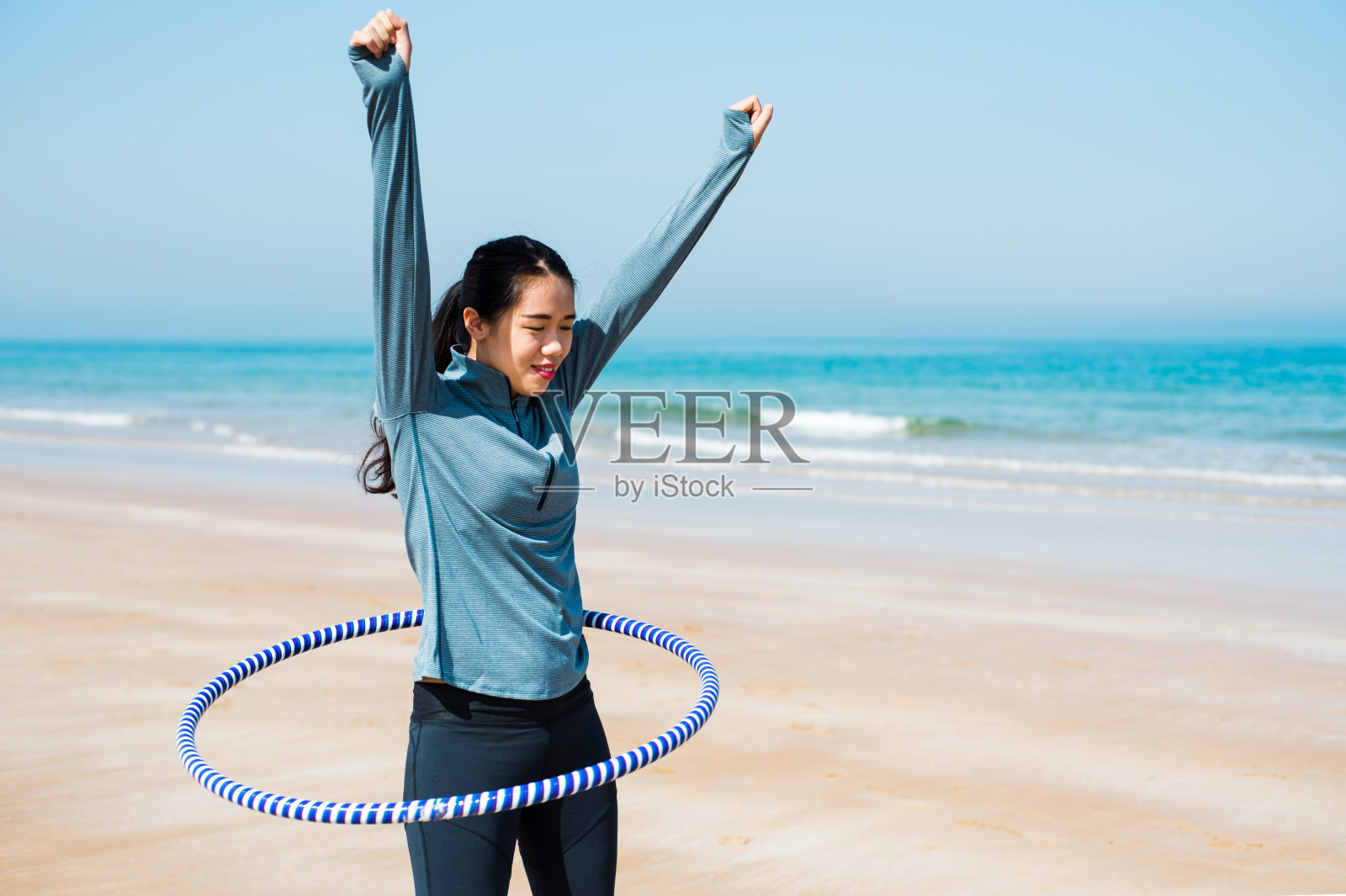 快乐的女人和呼啦圈在海滩上照片摄影图片