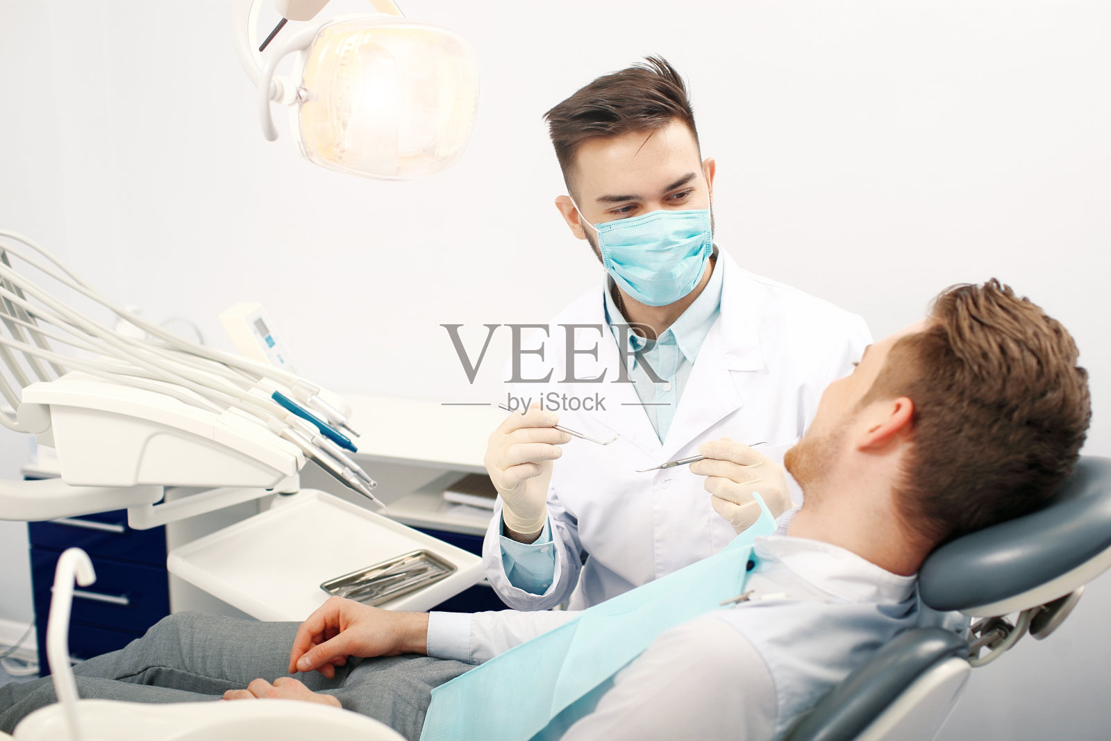 一个年轻的男牙医和一个病人照片摄影图片