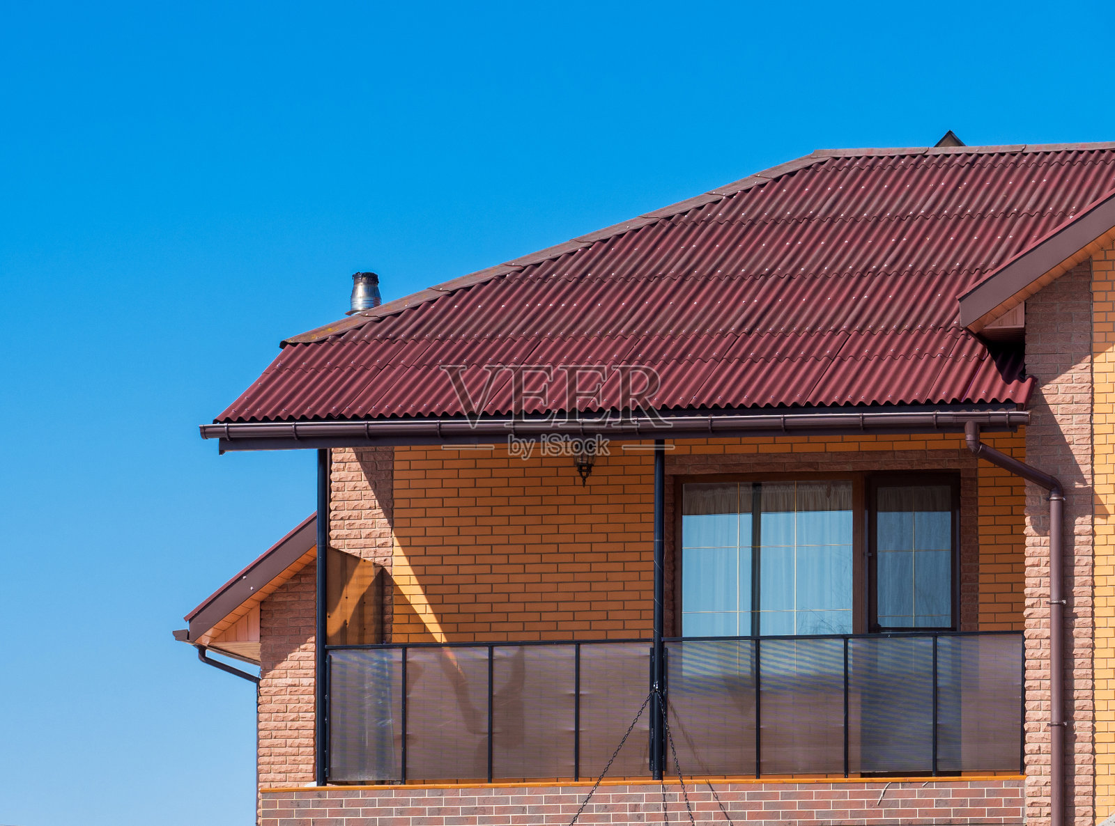 带有阳台和砖立面的现代小屋。蓝色的天空背景照片摄影图片