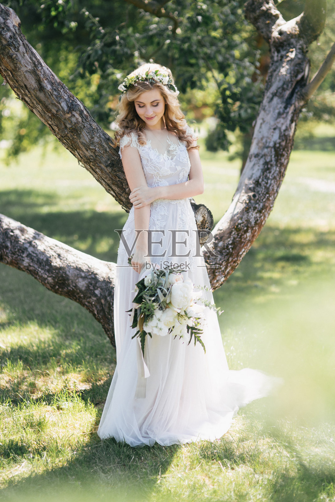 美丽的年轻新娘穿着婚纱捧着花束站在外面照片摄影图片