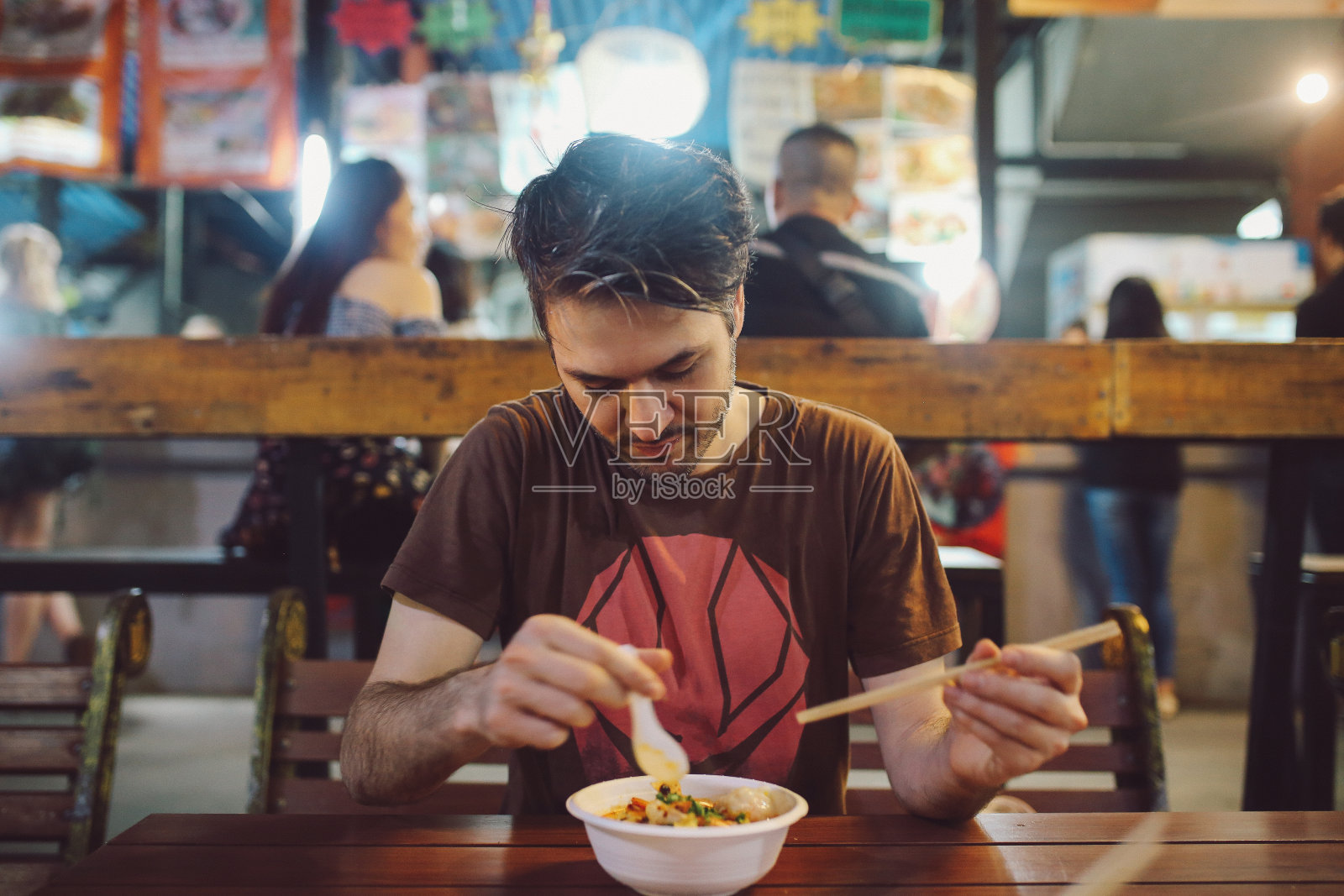 一个年轻人在泰国曼谷的街头市场上吃着正宗的泰国菜照片摄影图片