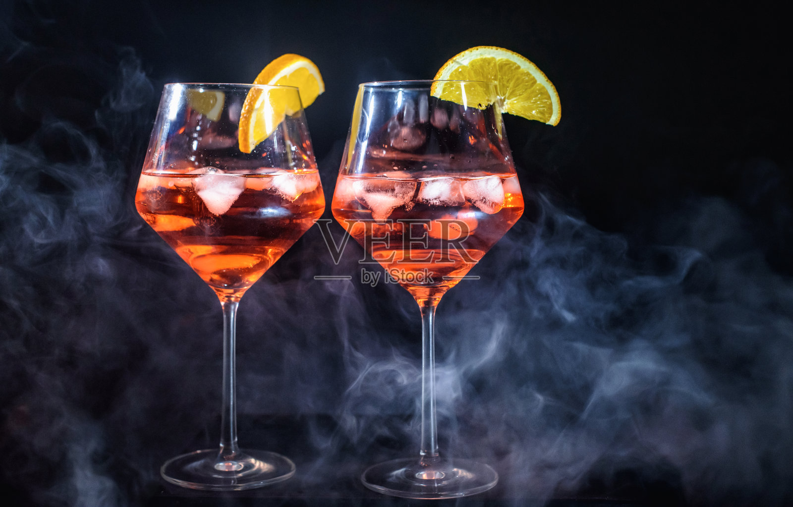 两杯Aperol香槟或鸡尾酒或葡萄孤立在黑色背景与橙色小叶烟飘飘派对庆祝主题照片摄影图片