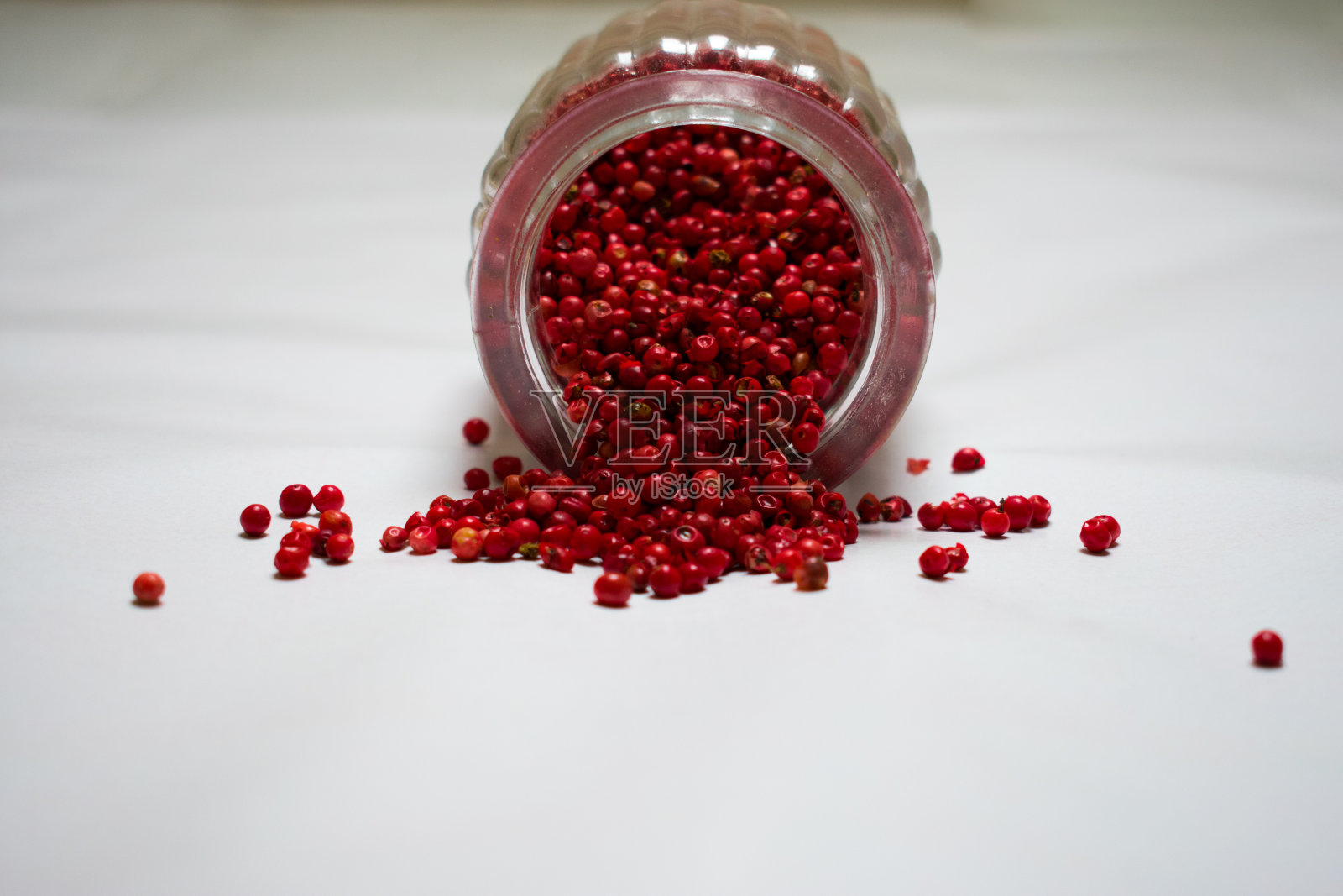 在白色背景下，红色胡椒从罐子里溢出照片摄影图片