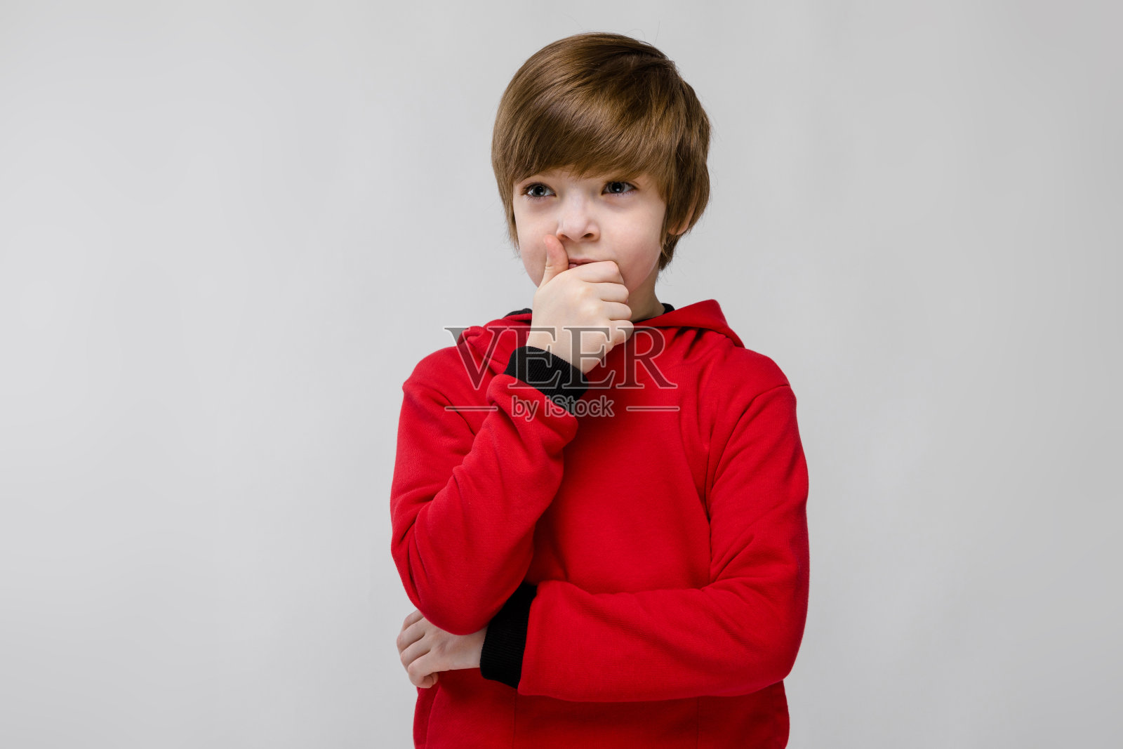 可爱自信的白人小男孩在红色毛衣思考灰色的背景照片摄影图片