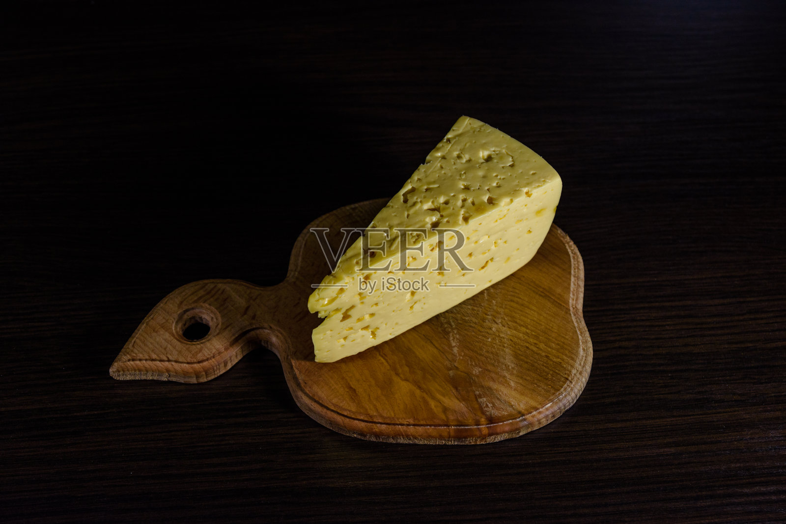 木板上放着一块奶酪照片摄影图片