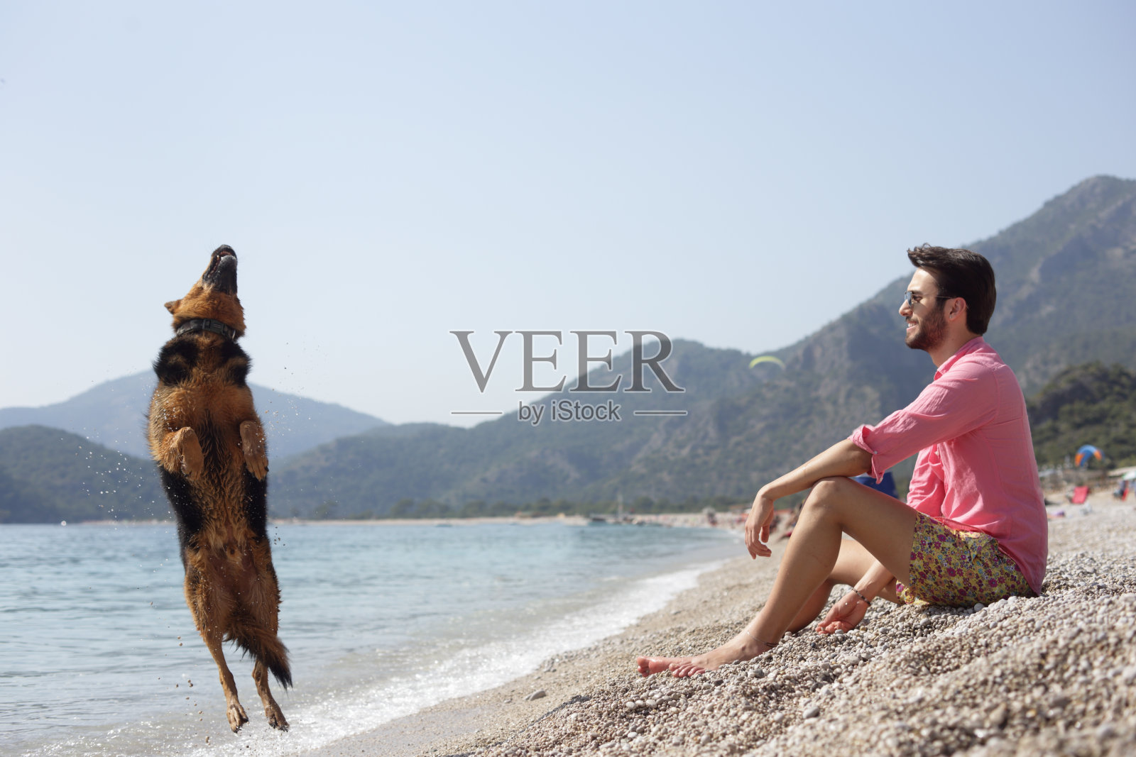这个年轻人在费特耶Ölüdeniz海岸和她的狗在一起照片摄影图片