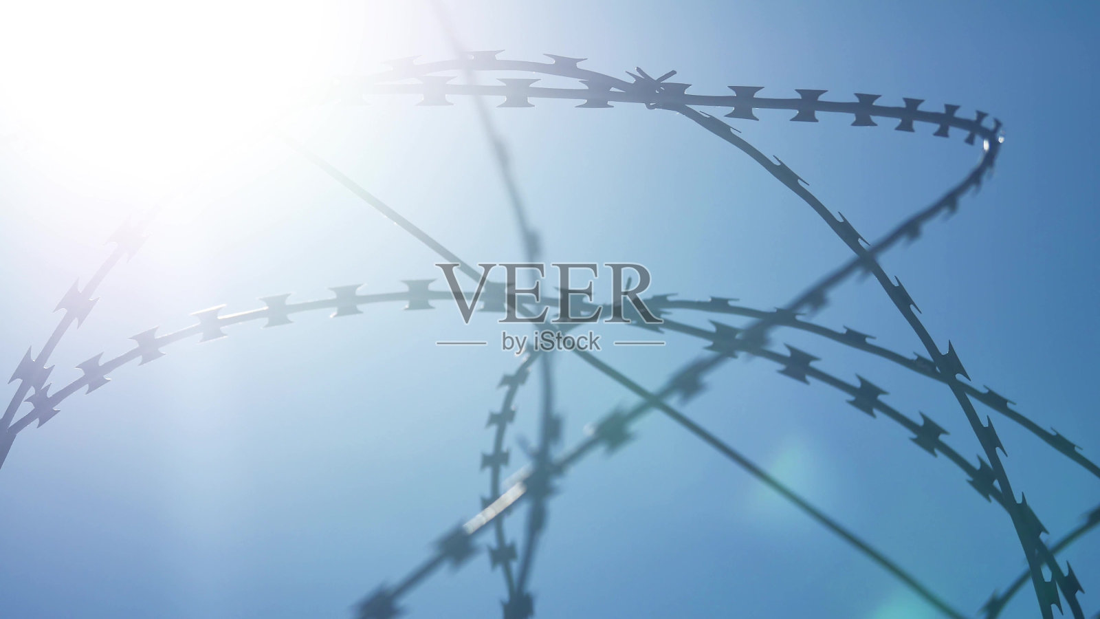 监狱的铁丝网上，刺眼的阳光映衬着集中营蓝色的天空照片摄影图片