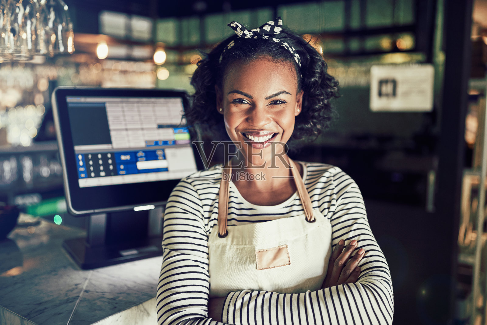 年轻的非洲女服务员在一家餐馆的柜台后面微笑照片摄影图片