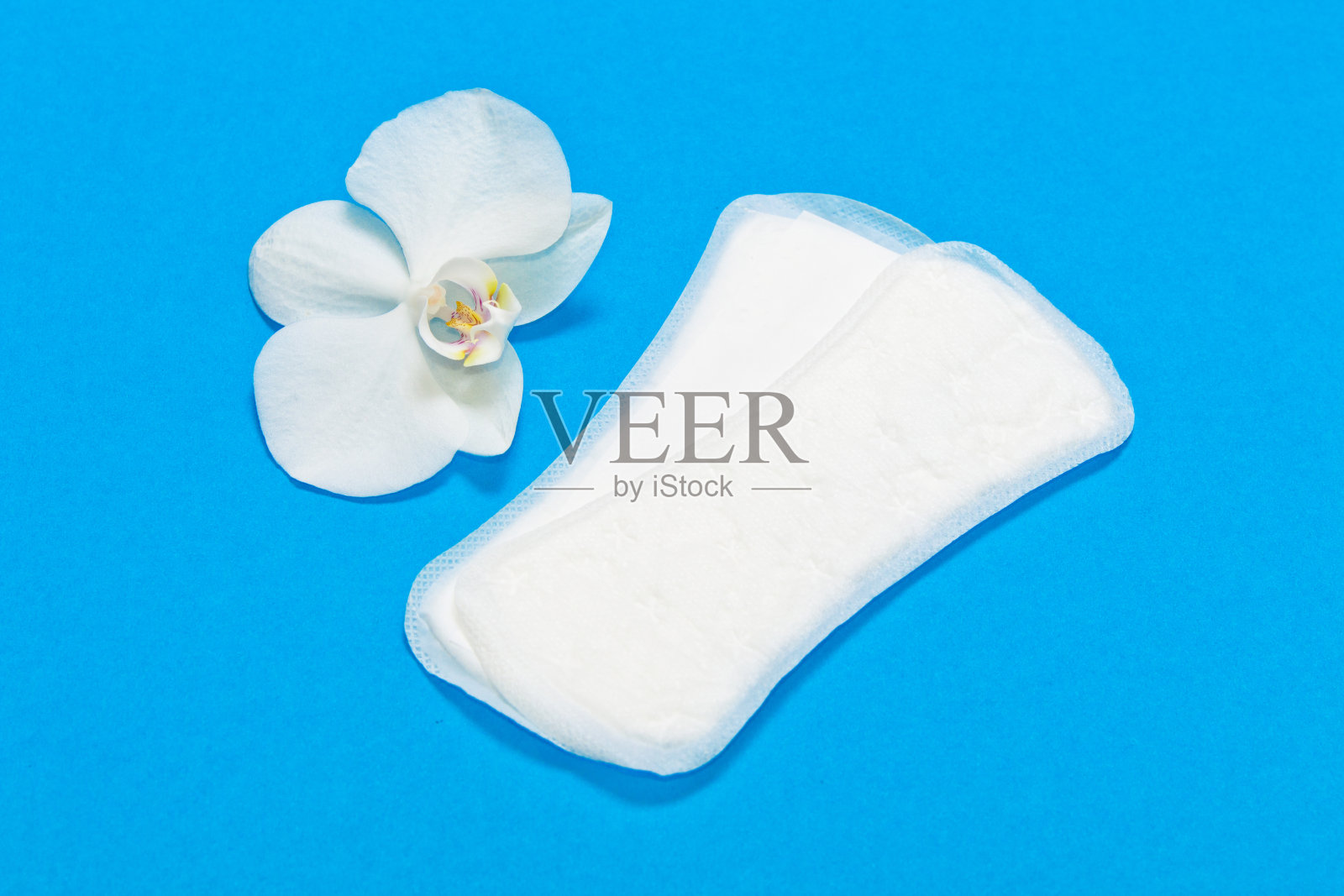 白色卫生巾和花白色兰花在蓝色的背景。照片摄影图片