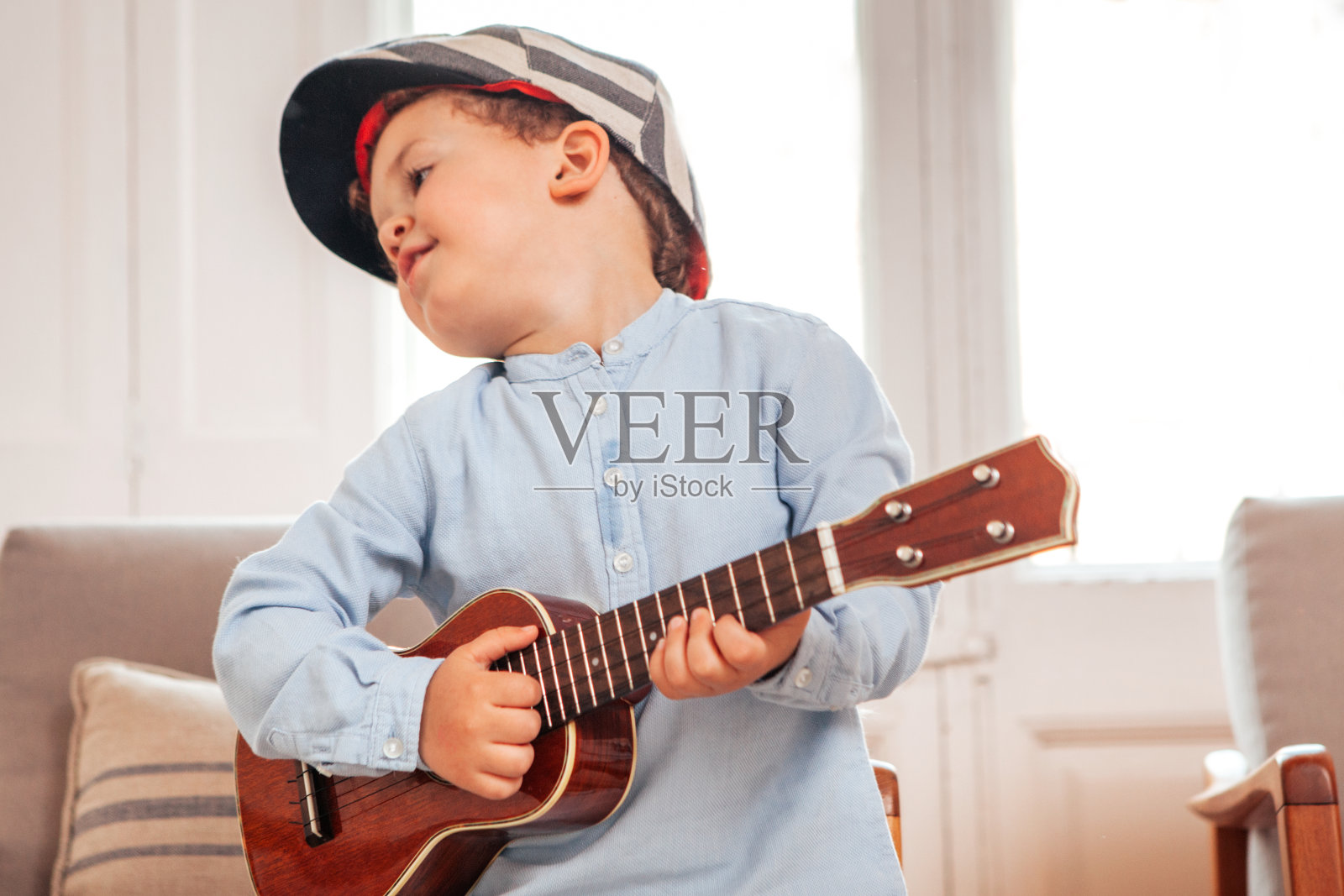 一个孩子在客厅里弹奏四弦琴照片摄影图片