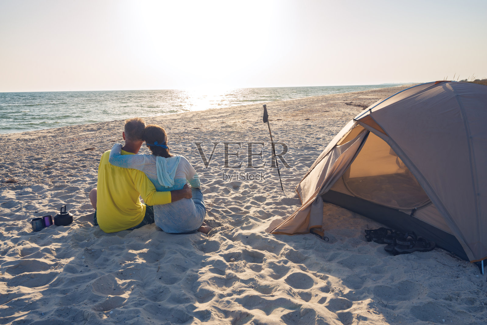 一对浪漫的旅行者正在海滩上的一个帐篷附近放松照片摄影图片