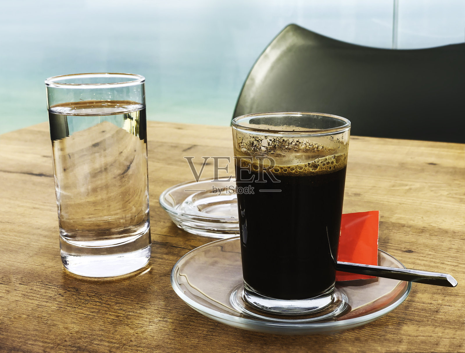 木桌上放着一杯浓黑的咖啡和一杯水照片摄影图片